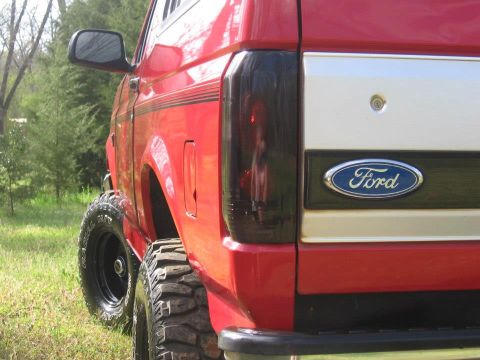 1992 Ford Bronco - Rear view of a red 1992 Ford Bronco, its iconic Ford badge and aggressive off-road tires.