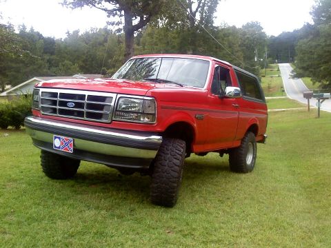 1992 Ford Bronco - This red 1992 Ford Bronco is shown from a 3q-front angle, parked on a grassy lawn.