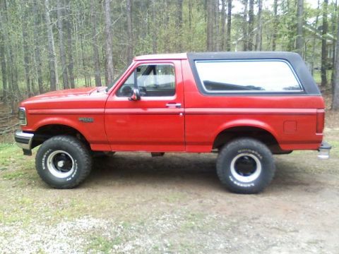 1992 Ford Bronco - Side profile of a red 1992 Ford Bronco with a black removable top.