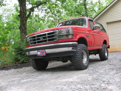 1992 Ford Bronco - This red 1992 Ford Bronco is parked on a gravel driveway next to a house and garage.