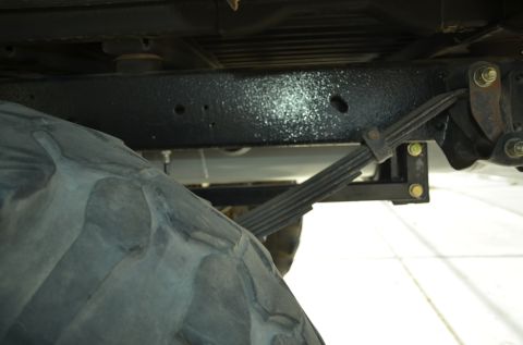 1979 Ford Bronco - Underside view of a vehicle's leaf spring suspension system and a large tire.