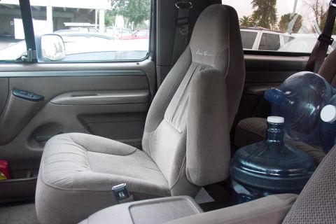 1992 Ford Bronco - The interior of a vehicle shows cloth seats and a large water jug, with a watermark at the bottom.