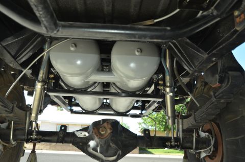 1979 Ford Bronco - The underside of a vehicle reveals a complex suspension system with prominent air tanks.