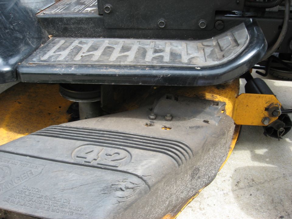 Lawn mower deck with 42 inscribed, showing yellow mounting bracket and black textured step