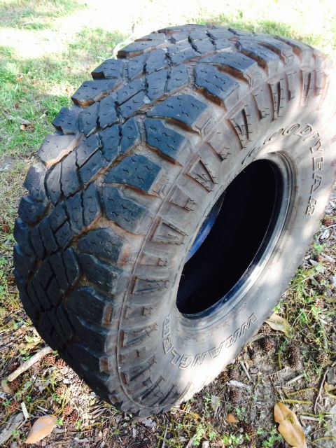 1979 Ford Bronco - Close-up of a Goodyear Wrangler off-road tire lying on the ground.