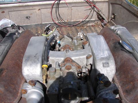 1973 Ford Ranchero - Engine parts piled in the bed of a truck, with rusty exhaust pipes visible.