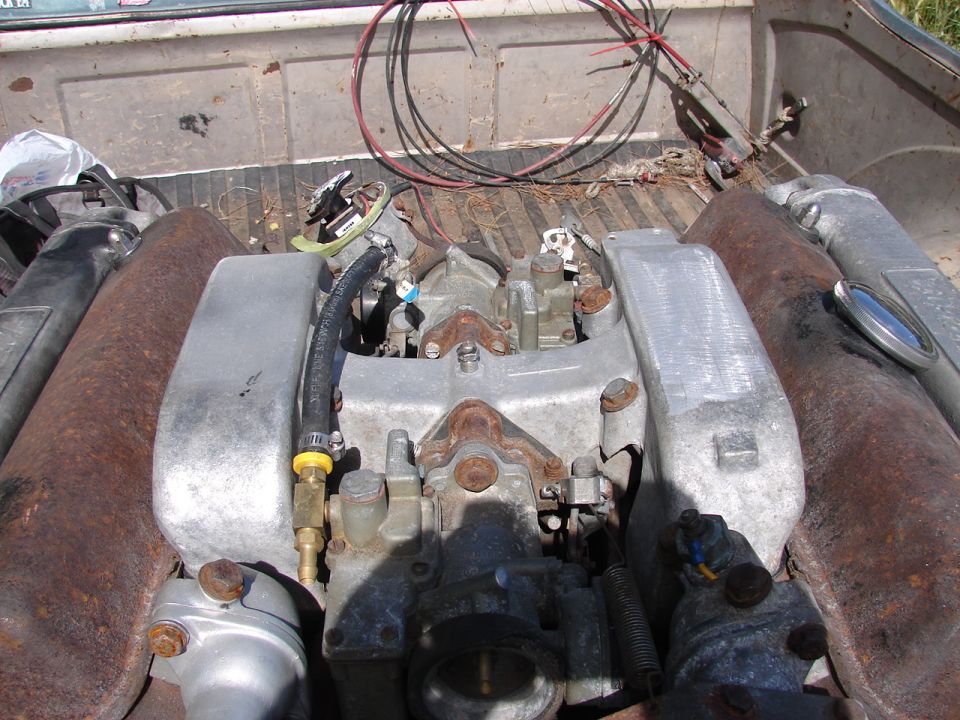 Engine components, including carburetors and exhaust pipes, in the bed of a pickup truck