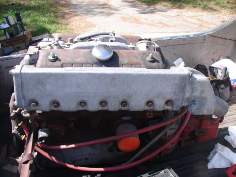 1973 Ford Ranchero - A V8 engine sits in the bed of a truck, showing its silver valve covers and red spark plug wires.