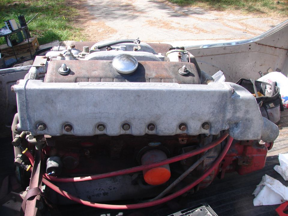 Close-up of a V8 engine with silver valve covers and red spark plug wires