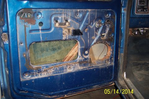1978 Ford Bronco - Interior view of a blue door panel, showing the window regulator and speaker mounting area.