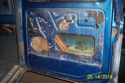 1978 Ford Bronco - Interior view of a blue car door panel, revealing the window regulator and door frame.