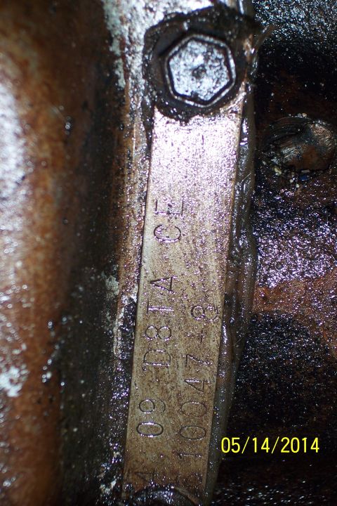 1978 Ford Bronco - A close-up view of a stamped metal part on an engine block, showing identification numbers.