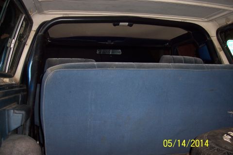 1978 Ford Bronco - The interior of a vehicle shows a blue bench seat and a roll bar.