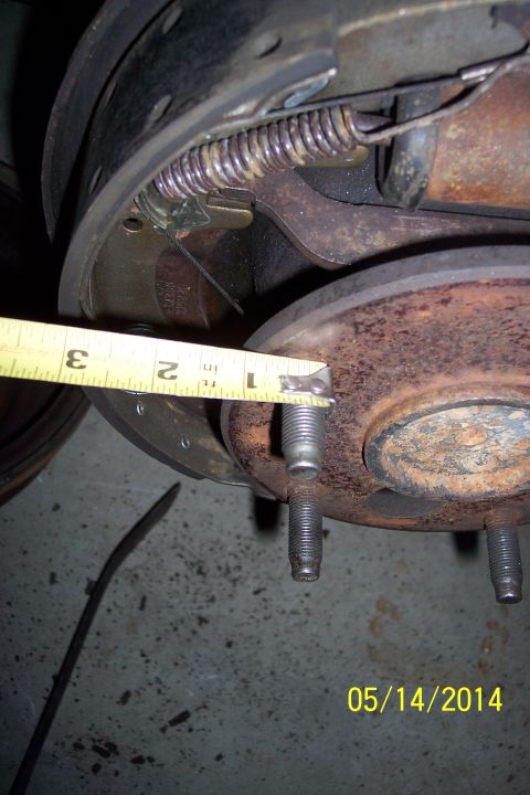 1978 Ford Bronco - Close-up of a brake drum being measured with a tape measure, showing brake shoes and springs.