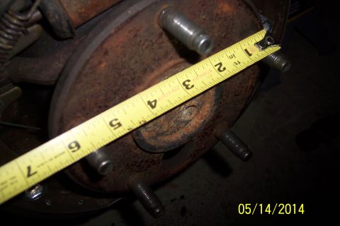 1978 Ford Bronco - Close-up of a rusty wheel hub with studs being measured by a tape measure.