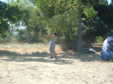1988 Ford Bronco - A person aims a slingshot outdoors near a tent and trees.