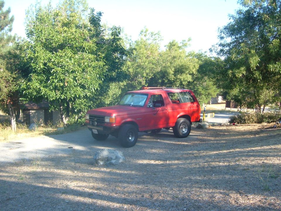 Red 1988 Ford Bronco parked in a campsite
