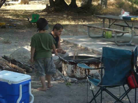 1988 Ford Bronco - Two people are gathered around a fire pit at a campsite, with a picnic table in the background.