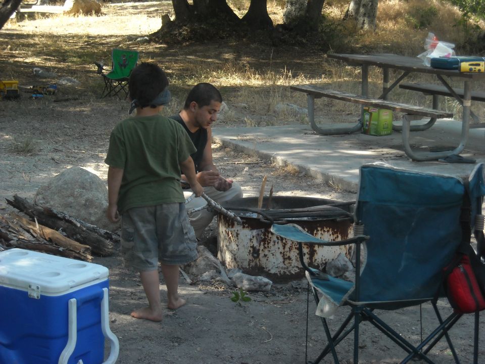 Camping scene with two people by a fire pit and picnic table