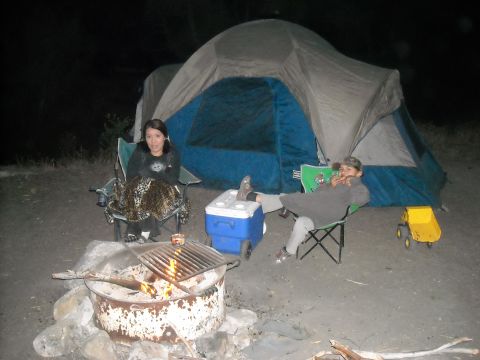 1988 Ford Bronco - Camping trip scene with a tent, campfire, and people relaxing.