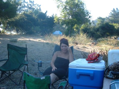 1988 Ford Bronco - A woman relaxes in a camping chair at a campsite, with a cooler and a tent visible in the background.