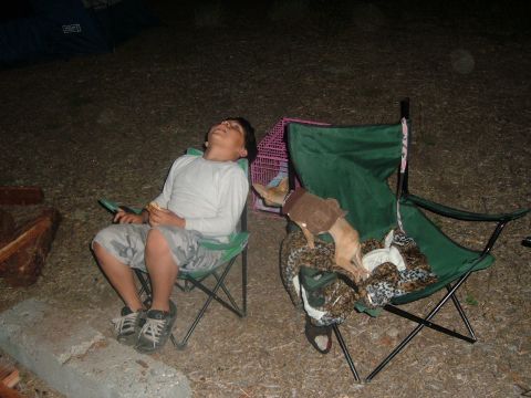 1988 Ford Bronco - A boy and a dog relax in camping chairs at a campsite.