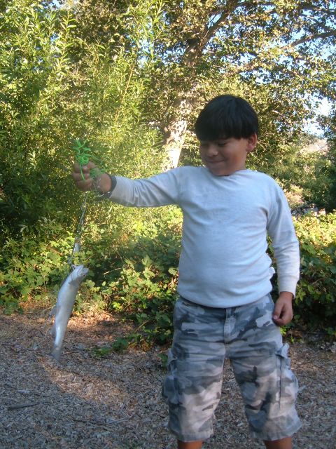 1988 Ford Bronco - A young boy proudly displays his catch of the day, a small fish, with a backdrop of lush greenery.
