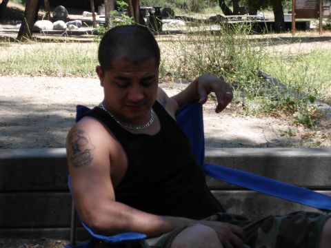 1988 Ford Bronco - A man relaxes in a camping chair outdoors, with trees and foliage in the background.