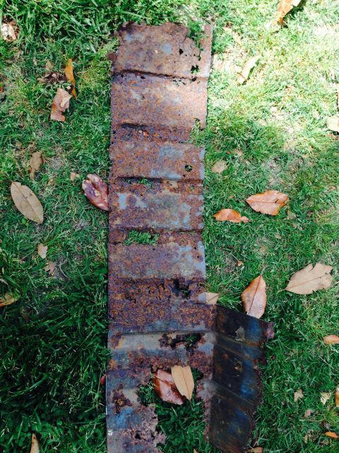 1979 Ford Bronco - This heavily corroded metal component is shown resting on a patch of grass with scattered autumn leaves.