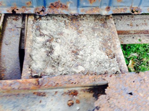 1979 Ford Bronco - This image shows a heavily rusted metal frame, likely from a vehicle, with accumulated dirt and debris.