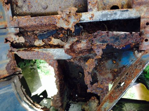1979 Ford Bronco - This heavily rusted frame section shows significant deterioration, with holes revealing blue paint beneath the corrosion.