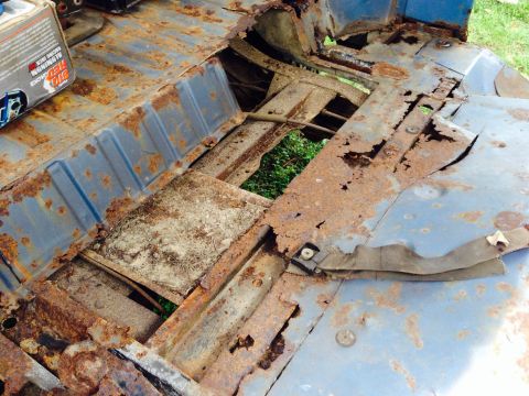 1979 Ford Bronco - The floor pan of this vehicle is heavily rusted, with large sections missing and exposing the ground below.