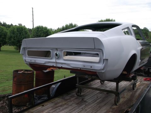 1967 Ford Mustang - Rear view of a 1967 Ford Mustang body undergoing restoration, mounted on a transport stand.