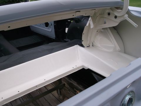 1967 Ford Mustang - The interior of a 1967 Ford Mustang trunk, showing white painted metal and a black fabric cover.