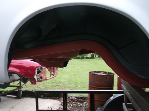 1967 Ford Mustang - View of a vehicle's wheel well and undercarriage, with the front of a red car visible in the background.