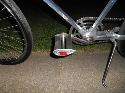Chrome bicycle pedal with red reflector and chainring