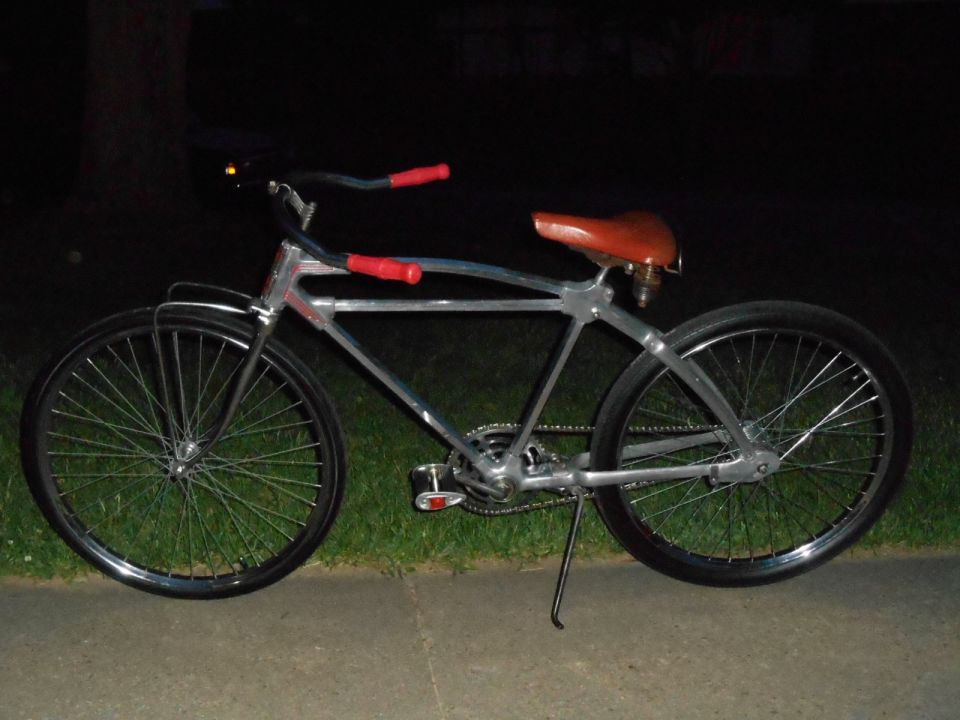 Custom bicycle with silver frame, brown seat, and red grips