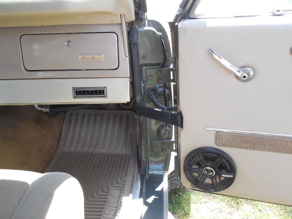 Bronco door open showing aftermarket speaker in white panel and Eddie Bauer glovebox badge
