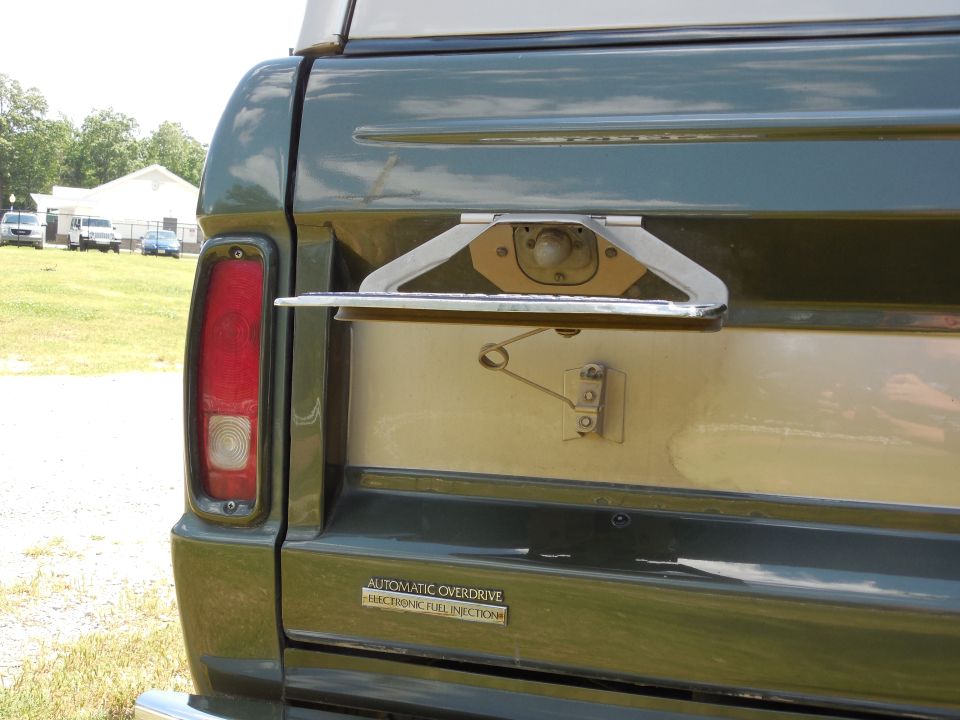 Green SUV rear with fold-down tailgate and 'AUTOMATIC OVERDRIVE ELECTRONIC FUEL INJECTION' badge