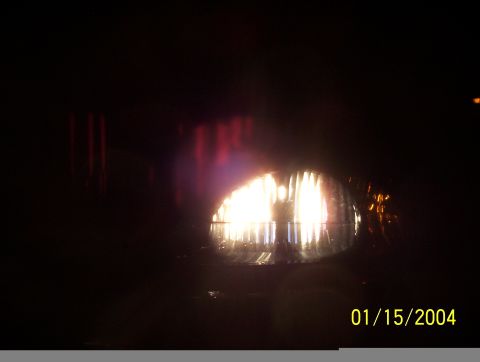 2003 Ford Taurus - A close-up view of a vehicle's illuminated headlight at night, with a date stamp of 01/15/2004 visible.