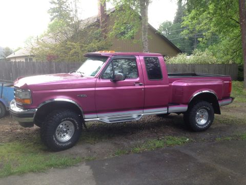 1992 Ford F-150 - A pink 1992 Ford F-150 pickup truck is shown from the side in a residential setting.