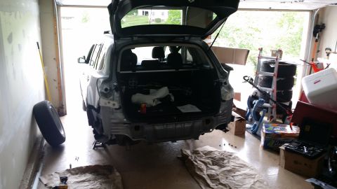2014 Subaru Outback - The rear bumper of a gray Subaru Outback is removed for repair or modification in a garage setting.