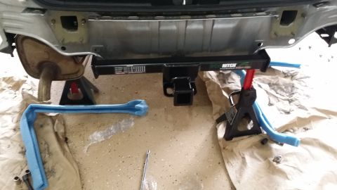 2014 Subaru Outback - A hitch receiver is installed on the rear bumper of a vehicle, which is elevated on jack stands.