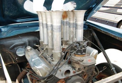 1968 Ford Mustang - Engine bay a V8 engine with an intake manifold fitted with eight individual carburetors and velocity stacks.
