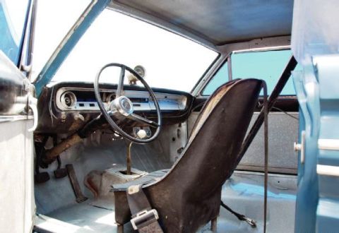 1968 Ford Mustang - The interior of a classic car shows a racing seat and a manual transmission shifter, with a clear view of the dashboard.