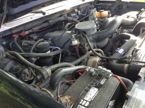 1995 Ford Bronco - Engine bay of a 1995 Ford Bronco, showing the battery, hoses, and alternator.