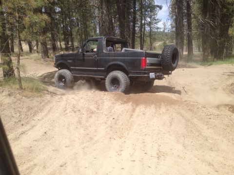 2005 Jeep Wrangler - A black Ford Bronco navigates a sandy off-road trail.