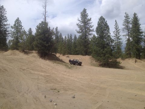 2005 Jeep Wrangler - A vehicle navigates a sandy terrain with tire tracks visible on the slopes.