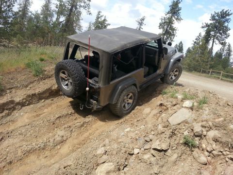 2005 Jeep Wrangler - A 2005 Jeep Wrangler navigates a rough dirt trail in a wooded area.