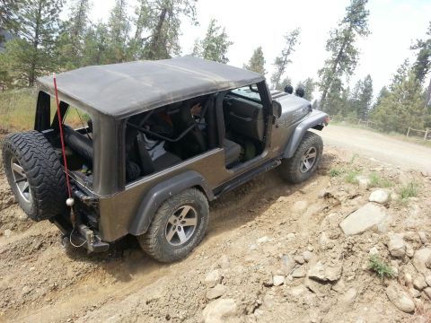 2005 Jeep Wrangler - A Jeep Wrangler navigates a challenging off-road trail with a dirt road ahead.